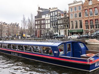 Amsterdam met rondvaartboot in de gracht en grachtenpanden