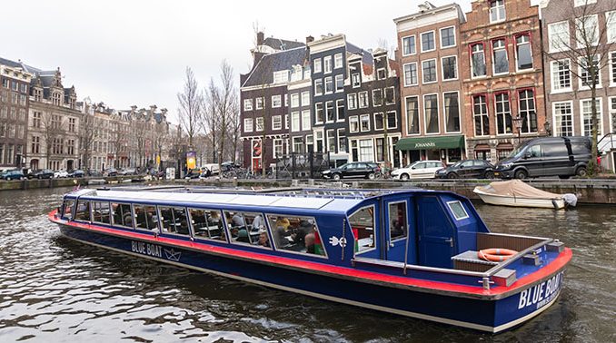 Amsterdam met rondvaartboot in de gracht en grachtenpanden